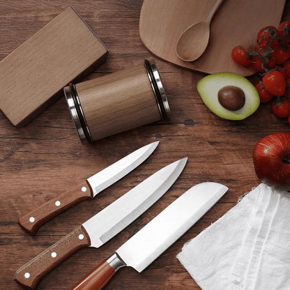 Three kitchen knives with wooden handles on a wooden surface with fruits and a cutting board.